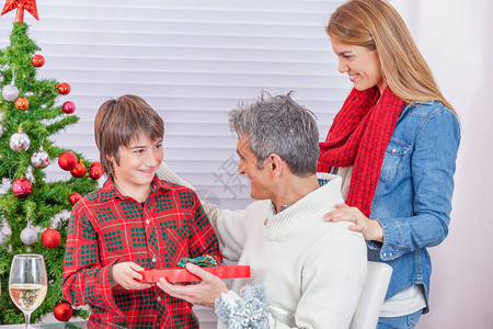 年轻男孩在家里接受家人的圣诞礼物图片
