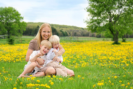 一位快乐的年轻母亲在夏日与她的两个孩子一起在一棵图片