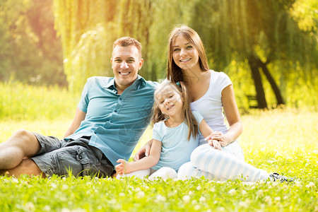 快乐的一家人坐在公园的草地上看图片