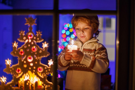 小男孩在圣诞节时站在窗边图片