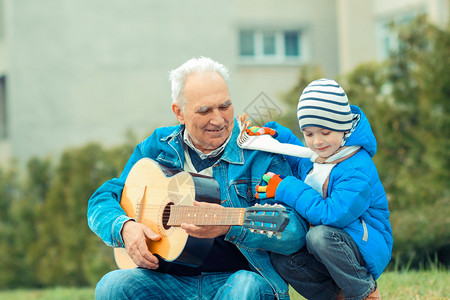祖父和孙子在公园户外弹吉他图片