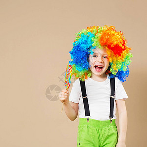 大五颜六色的假发的愉快的小丑男孩图片