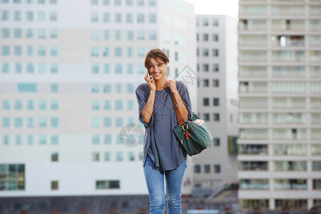 美丽的年轻女子在户外走路时打电话图片