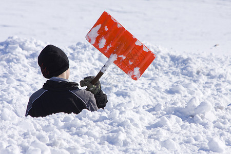 小男孩在雪地里嬉戏用铲子挖图片