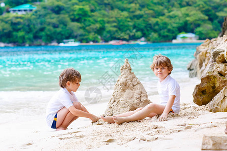 两个小男孩在塞舌尔热带沙滩上建沙堡玩得很开心图片