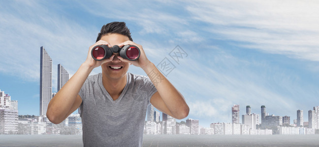 在城市的背景上一个男人拿着望远镜在观看图片