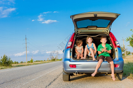 三个快乐的孩子在汽车家庭旅图片