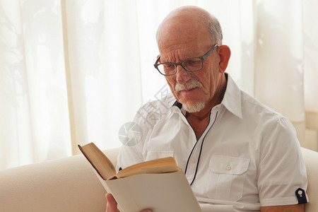 老人戴着眼镜在客厅看书图片