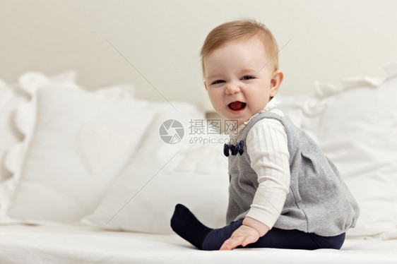 6个月女婴在床上玩耍和对着镜头微笑的肖像水平形状侧视图全长图片