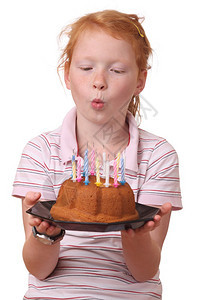 小女孩在她的生日蛋糕上吹蜡烛图片