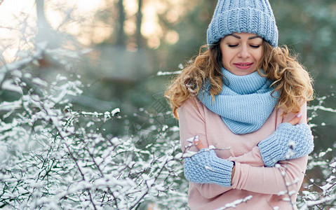 美丽的微笑女人的冬天肖像与雪花蓝色手套和针织毛衣背景图片