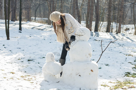 冬季在户外堆雪人的女性图片