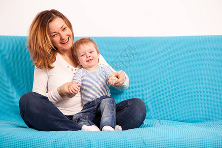 快乐微笑的母亲和儿子在沙发上共度优美时光图片