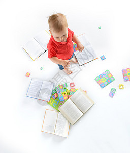 坐在书本和字母谜题中的小男孩图片
