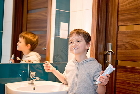 孩子在洗手间刷牙左手握牙膏穿着灰色图片
