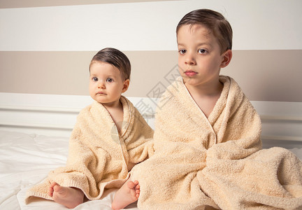 洗完澡后坐在床上的毛巾下面的小男孩和图片