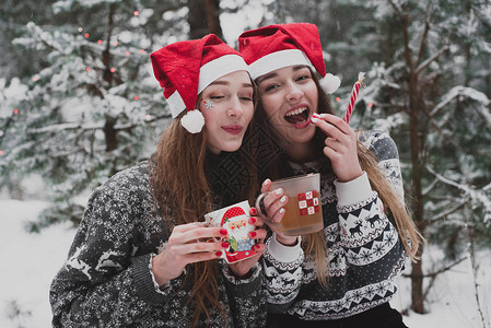 下雪天在户外戴圣诞帽拍照的漂亮女孩们图片
