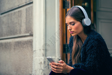 年轻女在街上通过在线音乐应用程序图片