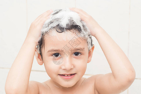 黑发男孩用洗发水洗头背景图片