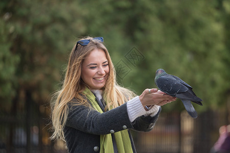 女孩在公园里喂鸽子背景图片