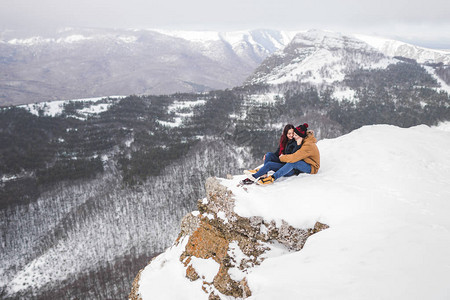 一对坐在山悬崖边的夫妇风景美图片