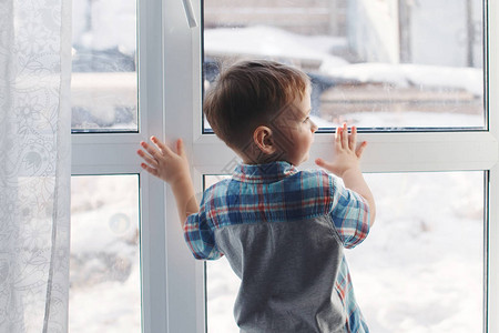 窗边的小男孩望着街道做梦背景图片