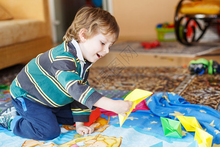 有趣的4岁男孩在家里玩纸船背景图片