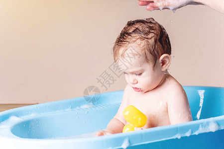 在浴室的蓝浴缸里洗可爱的男孩小孩在玩黄图片