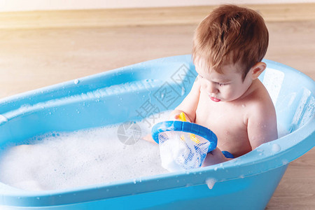 小可爱男孩在浴室的蓝浴缸里洗衣服孩子玩图片
