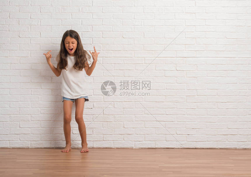 年轻的西班牙小孩在白砖墙上挥舞着疯狂的表情喊叫图片