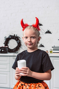 以红色魔鬼角举着蜡烛在家中握手的小孩肖像图片