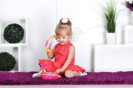 金发女孩穿裙子在玩具电话上说背景图片
