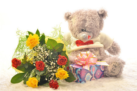 带着一束鲜花和一份礼物的泰迪熊图片