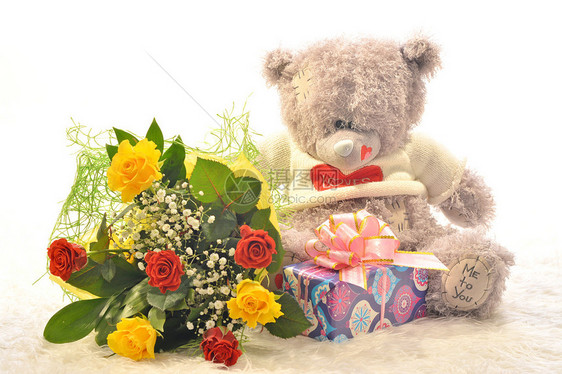带着一束鲜花和一份礼物的泰迪熊图片