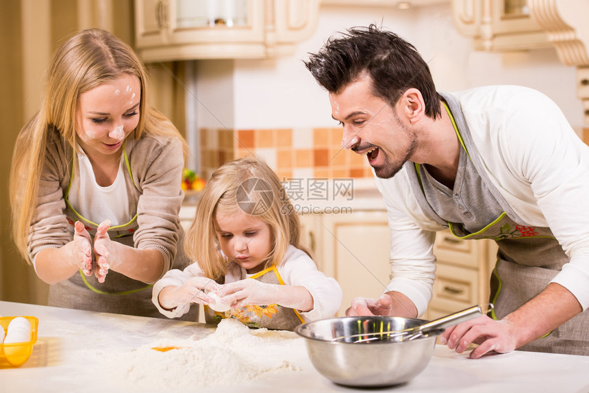 快乐的父母和他们年轻的女儿正在做饭在家图片