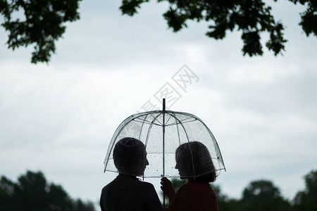 公园两个女孩在雨中撑伞闲聊图片