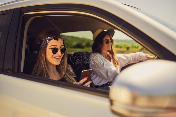 两个女孩在车里开车一个驾驶和另一个使用智图片