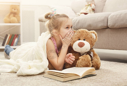 带着泰迪熊阅读书和与她最爱的玩具朋友分享秘密的可爱小姑娘图片