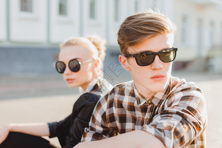 特写时尚肖像的年轻夫妇在城市街头摆在夏季风格的衣服复古太阳镜时尚夫妇在太阳镜时尚服装秋季衣服背景图片