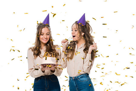 穿着生日帽子的快乐双胞胎看着在落下来的彩色蛋糕下图片