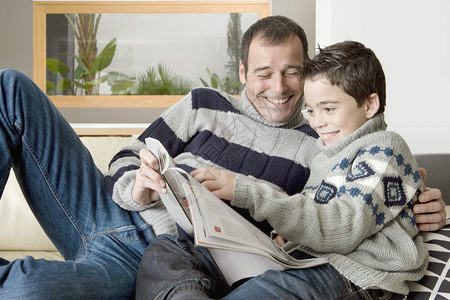 爸和儿子一边看杂志一边在的沙图片