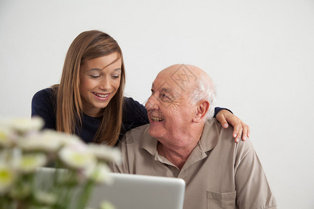女孩帮助她的祖父用电脑图片