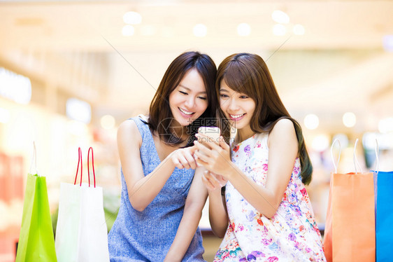 在购物中心看智能电话的开心女人图片