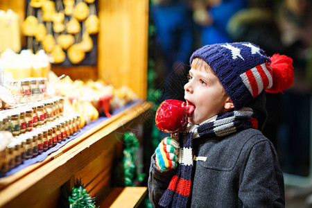 可爱的小男孩在甜食旁边吃糖苹果图片素材