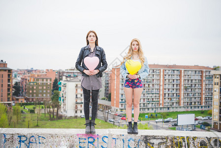 两个美丽的金发美女和黑褐色女孩在城市郊区玩气球图片
