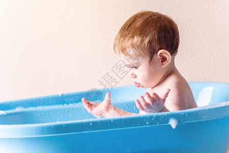 小可爱男孩在浴室的蓝浴缸里洗衣服孩子玩图片