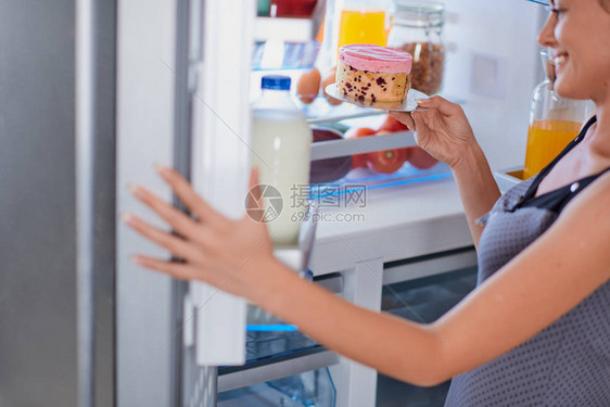 女人从冰箱里拿芝士蛋糕来断食满图片