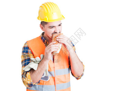 戴着防护头盔的男建筑师在白底休息时吃着美味的图片
