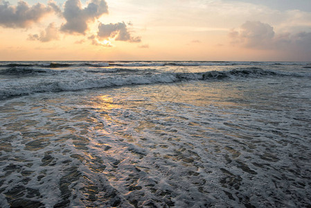 热带岛屿上波涛汹涌的大海上的宁静日落图片