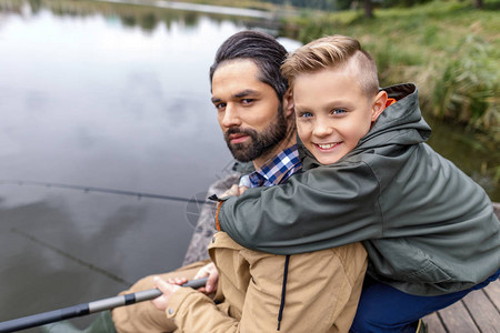 和微笑的儿子在湖边木码头上钓鱼图片